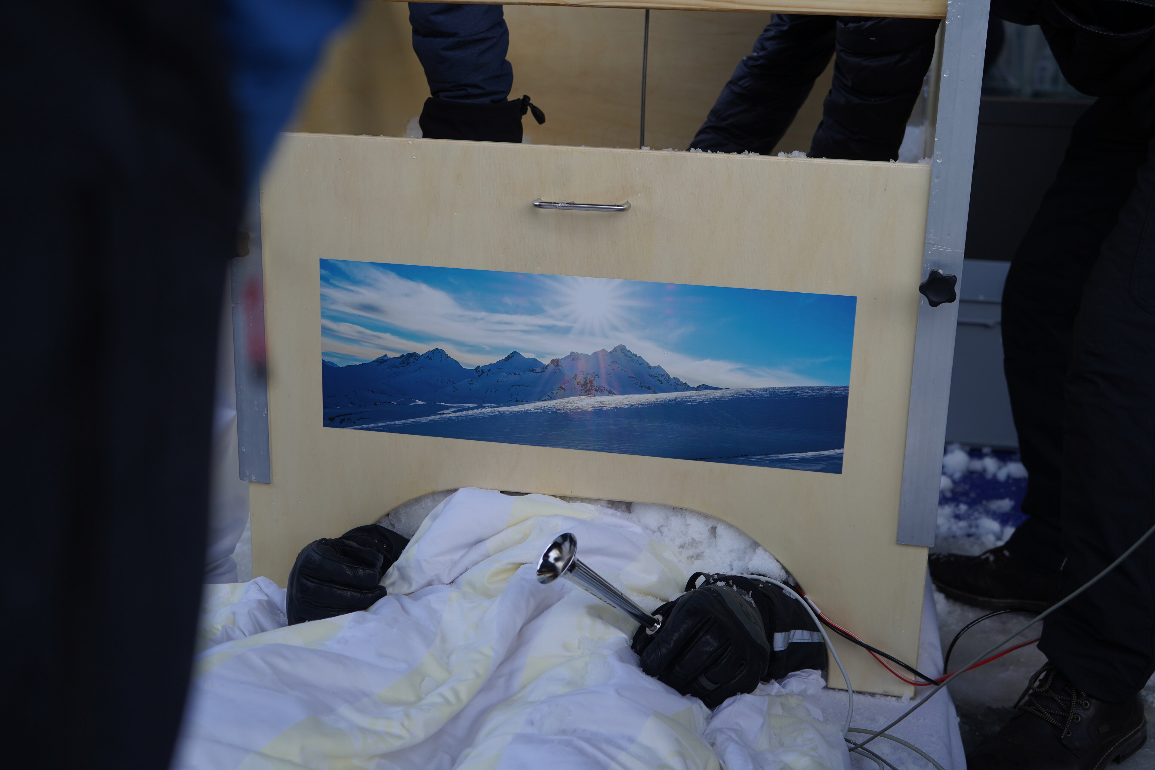 Die selbst gebaute Kiste, die den Schnee über dem Oberkörper sammelt, wurde mit schönen Bergbildern verziert.